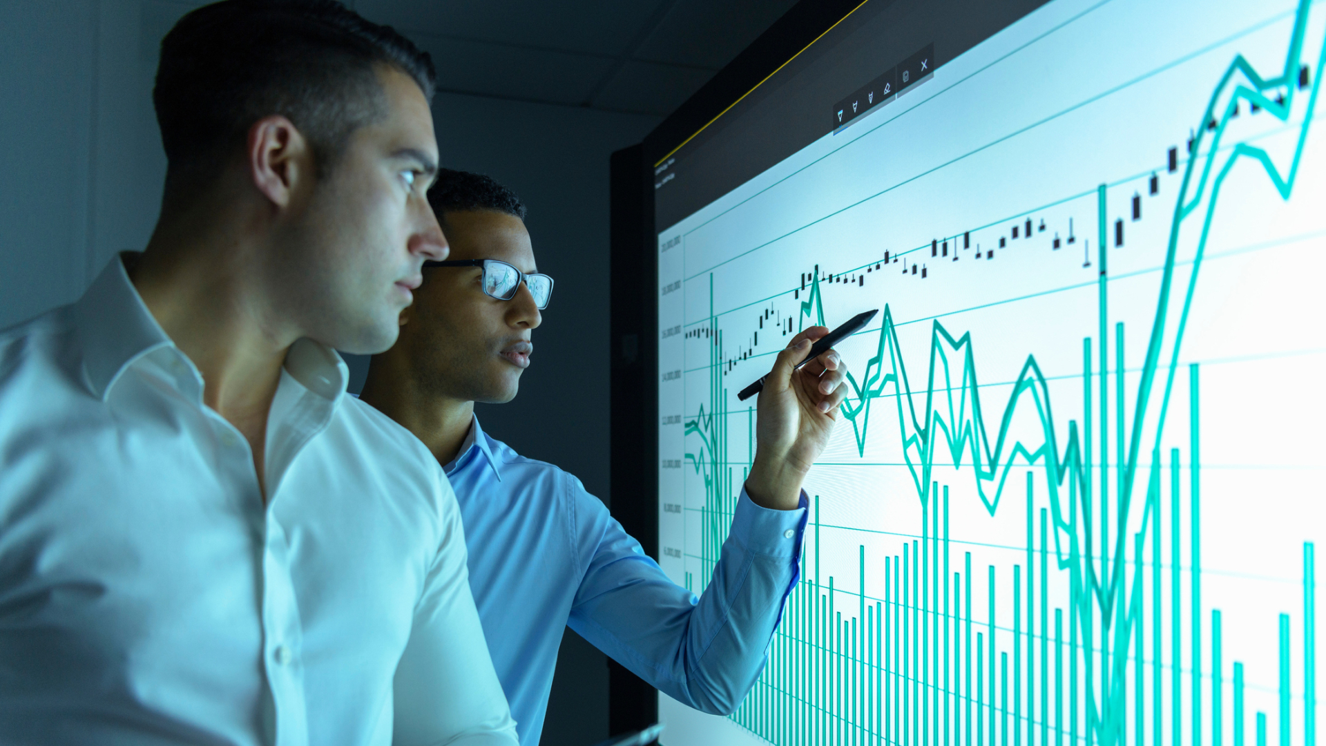 Businessmen studying graphs on an interactive screen in business meeting